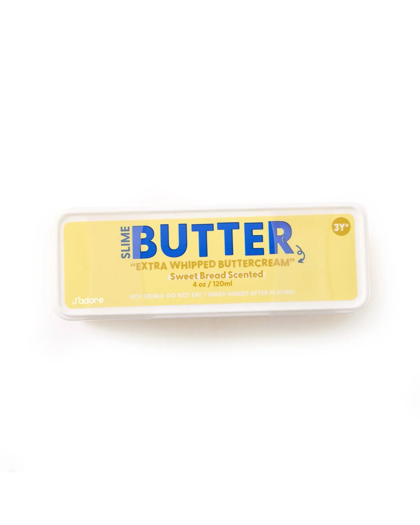 A rectangular container labeled Jadore Butter Slime - “Extra Whip”: Extra Whipped Buttercream, Sweet Bread Scented, 4 oz. This butter slime is ideal for sensory play and stress relief. The label displays yellow and blue text with a note indicating it’s suitable for ages 3 and up.