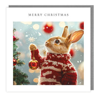 Rabbit Decorating the Tree Christmas card with rabbit in festive jumper holding a red bauble