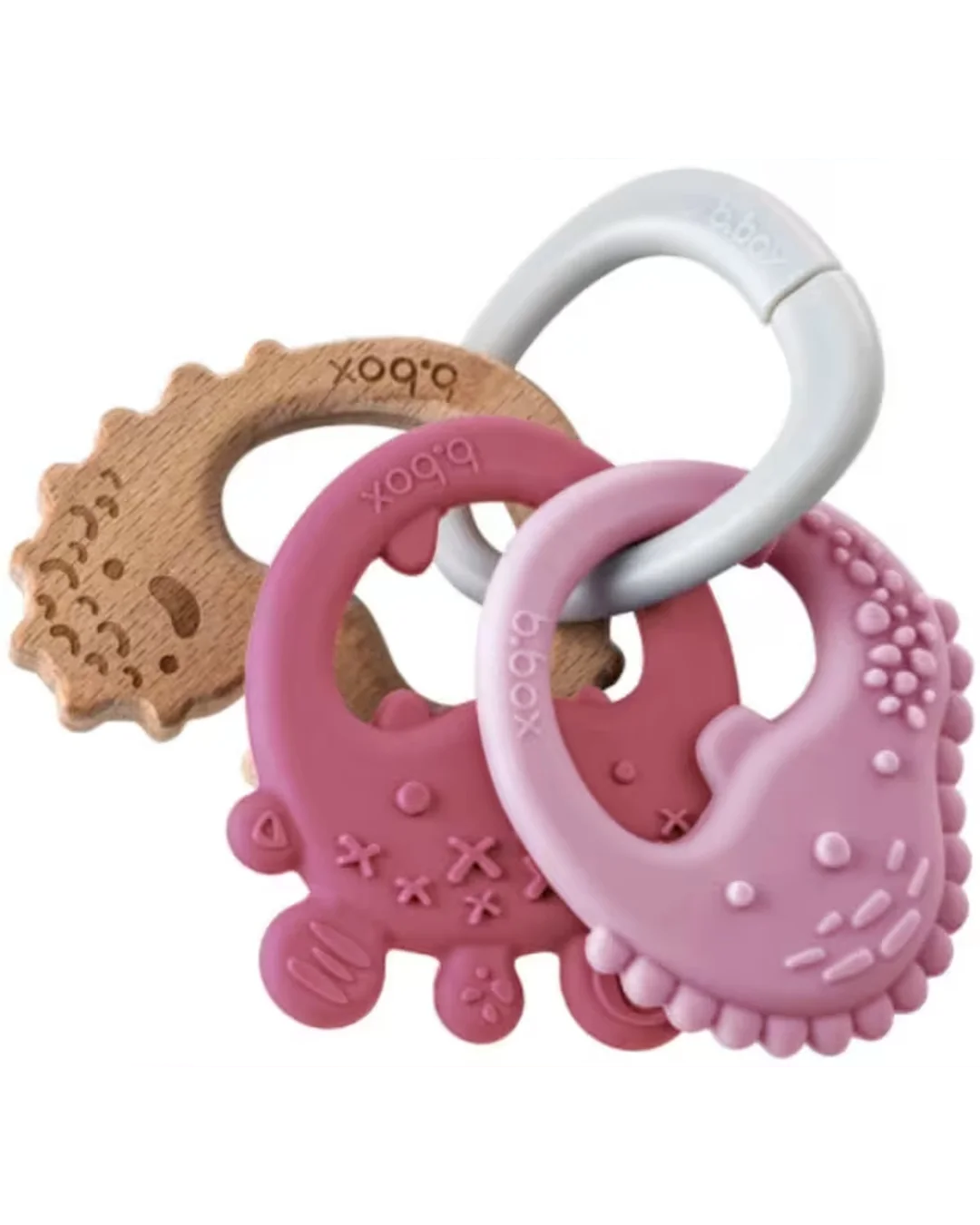 Three b.box baby teething toys arranged together on a white background: a natural wood bear-shaped teether, a pink silicone bear teether, a pink silicone moon teether, and a white carabiner ring.
